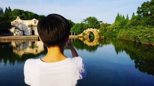 Rear view of woman looking at lake against sky