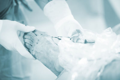 Cropped image of surgeon removing medical equipment from patient foot in operating room