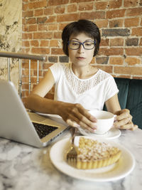 Portrait of smiling young woman having breakfast at table