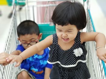 High angle view of cute siblings in shopping cart