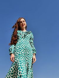 Low angle view of woman standing against blue sky