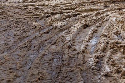 Thick dirty wet snow layer with many car wheel tracks on winter street - full frame background