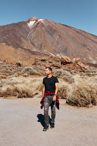 Full length of man looking away while walking on land against mountain and sky