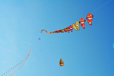 Low angle view of kites flying against clear sky