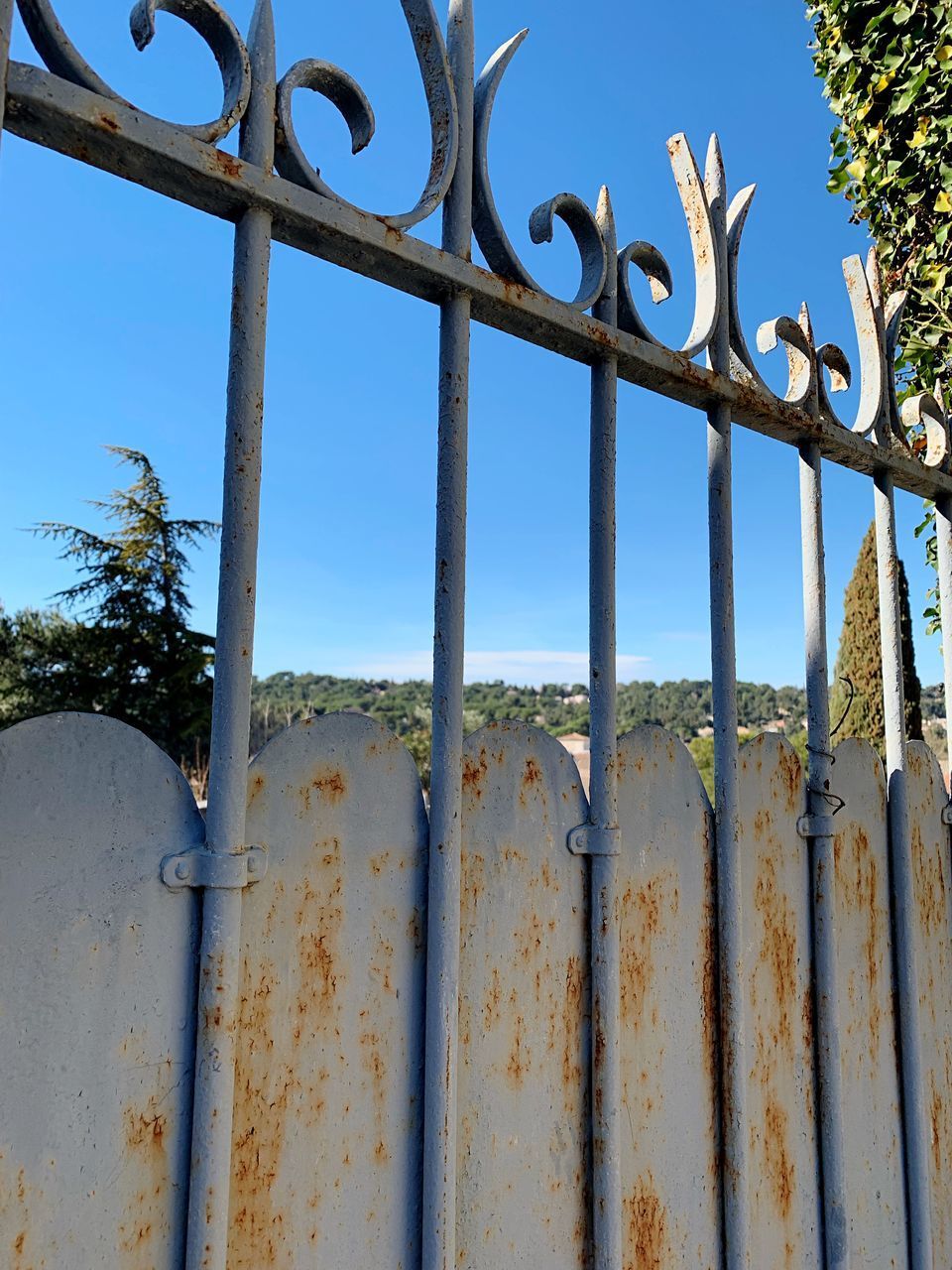 LOW ANGLE VIEW OF RUSTY FENCE AGAINST BLUE SKY