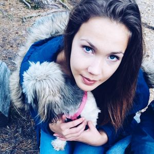 Portrait of young woman with dog sitting outdoors