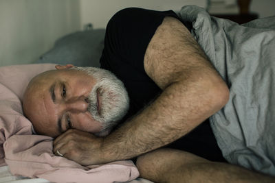 Stressed mature man lying down on bed at home