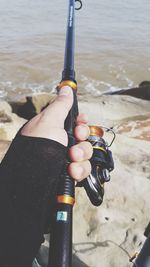 Cropped hand holding fishing in sea