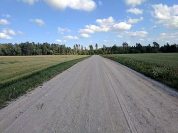 Road amidst agricultural field against sky