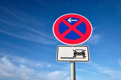 Low angle view of road sign against blue sky