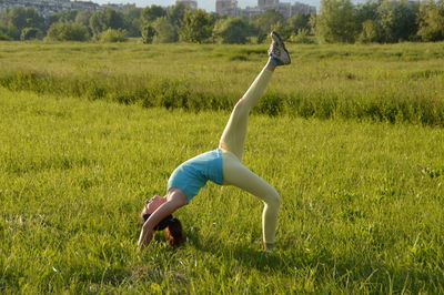 Full length of woman stretching on grassy field