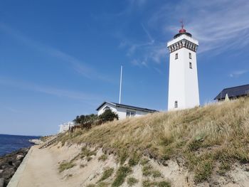 Lighthouse by sea against sky