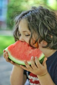 Boy eating watermelon while sitting at yard