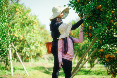 Rear view of woman standing by plants against trees