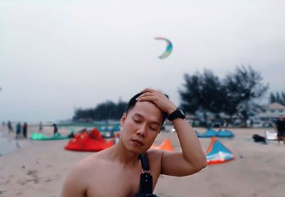 Young man on beach against sky