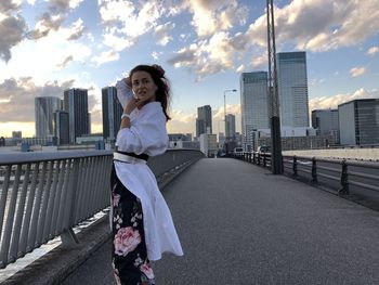 Woman standing on bridge against cityscape