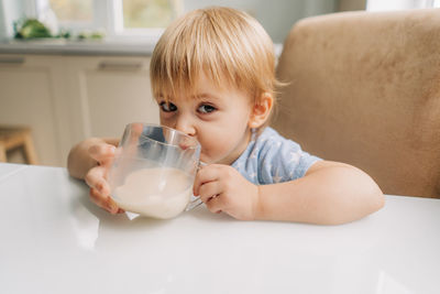 Portrait of young woman drinking milk at home