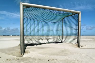 Empty deck chairs on beach against sky