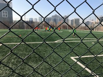 View of cityscape through chainlink fence