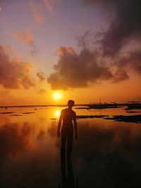 Silhouette man standing on beach against sky during sunset