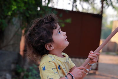 Profile view of a little child holding a wooden stick and looking at it