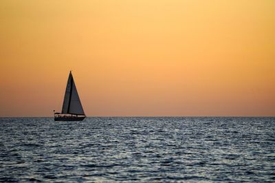 Sailboat sailing on sea against sky during sunset