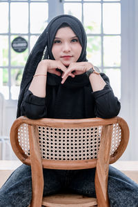 Portrait of young woman sitting on sofa at home