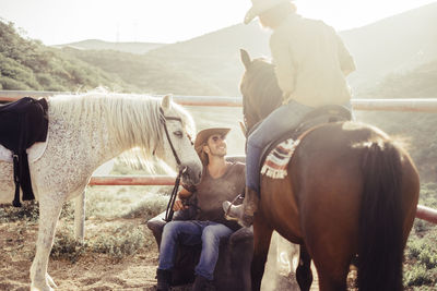 People with horses sitting against mountains