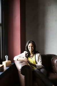 Portrait of woman sitting on armchair in office