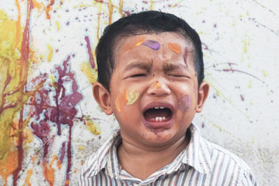 Cute boy crying while painting wall 