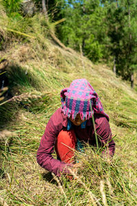 Indian female farmer working in the fields, cutting the grass wearing traditional dress.