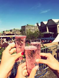 Cropped hands of friends toasting drinking glasses in city