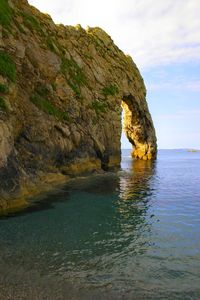 Rock formation in sea against sky