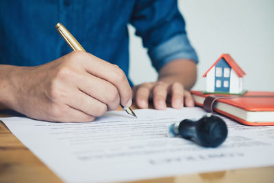 Midsection of man signing contract on table