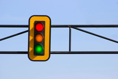 Low angle view of illuminated stoplight against clear blue sky