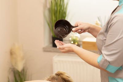 Midsection of woman holding bottle while sitting at home