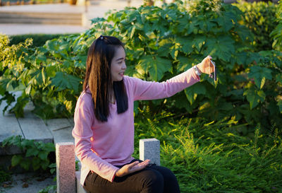 Portrait of young woman standing against plants