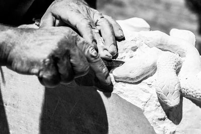 Cropped hands of male worker carving snake sculptures on stone
