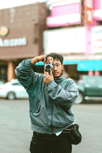 Full length of young man photographing while standing on street