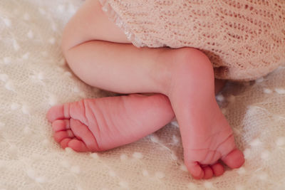 Low section of newborn baby on bed at home