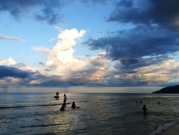 Silhouette people on sea against sky