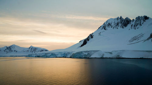 Scenic view of snowcapped mountains against sky during sunset