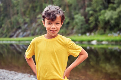 Portrait of smiling boy standing against water