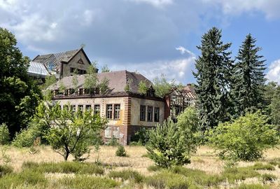 Old building by trees against sky