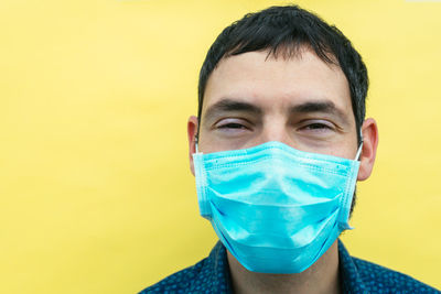 Young smiling man wearing a mask on a yellow background
