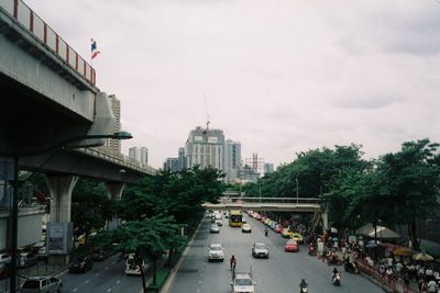 Vehicles on road by buildings against sky