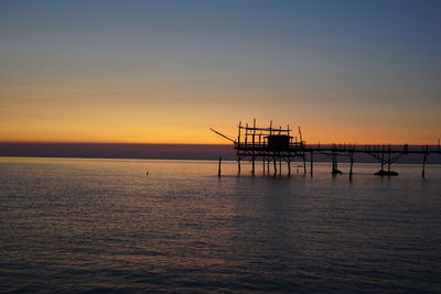 Silhouette ship in sea against sky during sunset