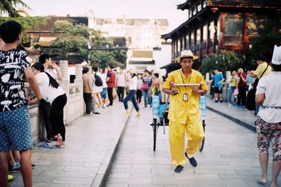 Rear view of people walking on street in city
