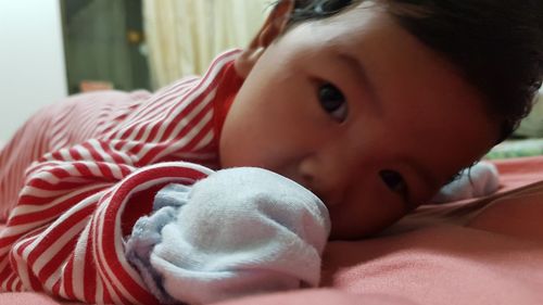 Close-up portrait of cute baby lying on bed