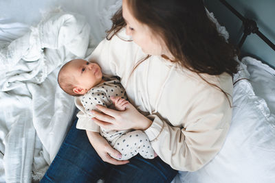 High angle view of mother and daughter sitting on bed at home